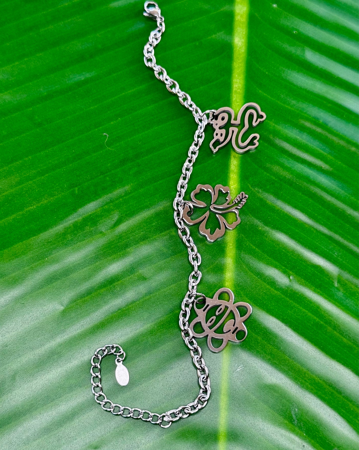 Stainless steel bracelet with Coquí Taíno, Flor de Maga, and Sol Taíno charms in gold or silver.