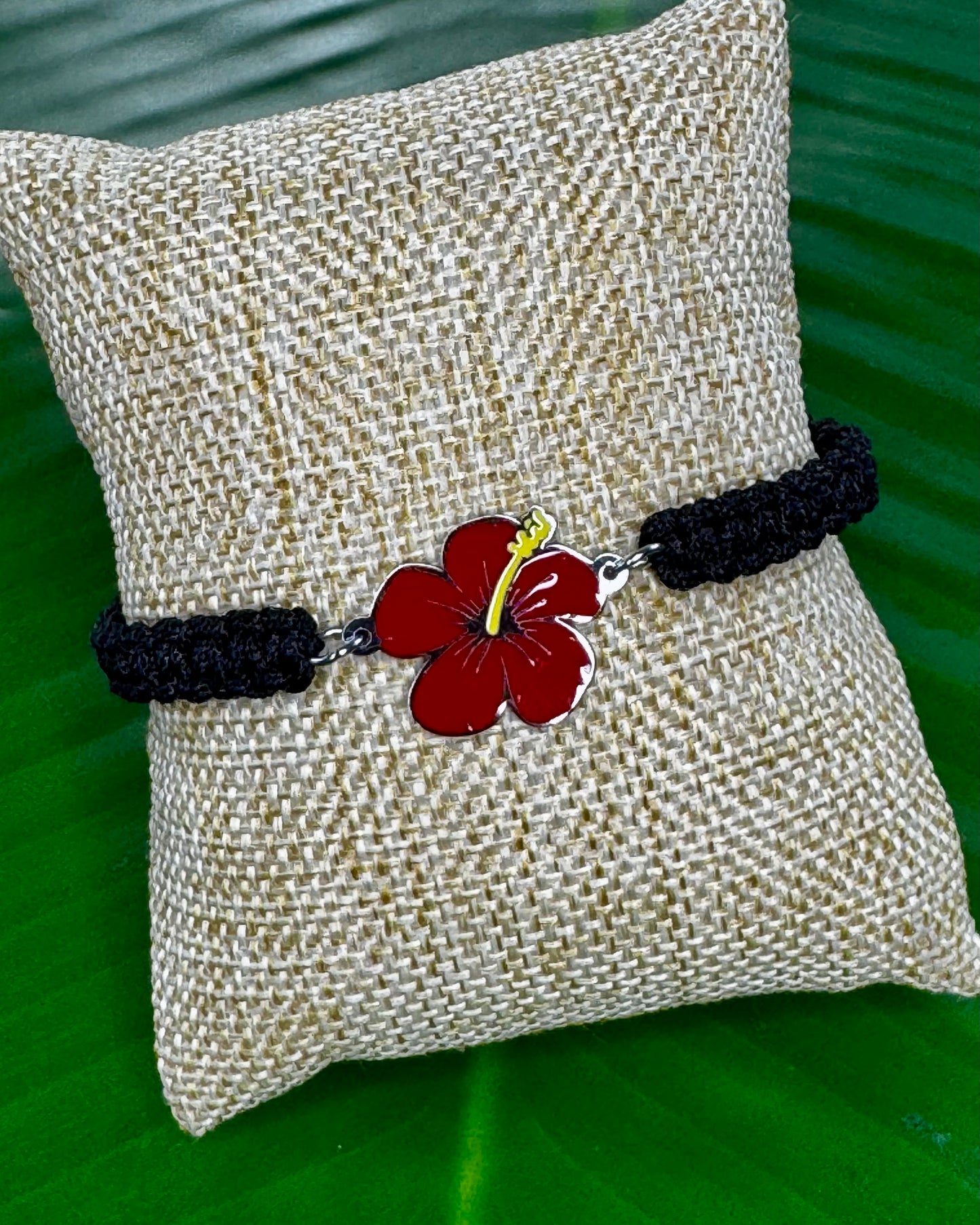 Black adjustable thread bracelet with a gold or silver Flor de Maga charm displayed on a neutral background.