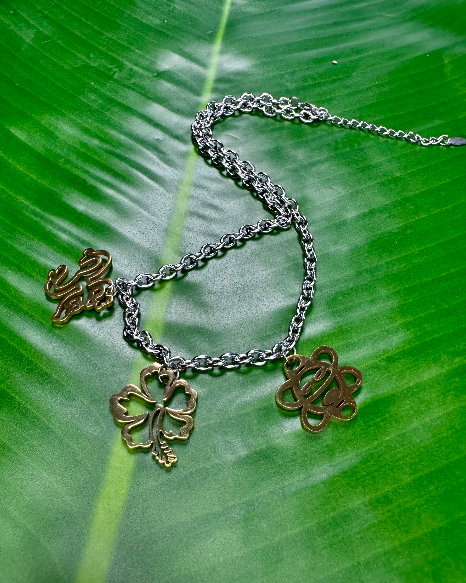 Two-tone Puerto Rican necklace with Coquí, Flor de Maga, and Sol Taíno charms on a stainless steel chain.
