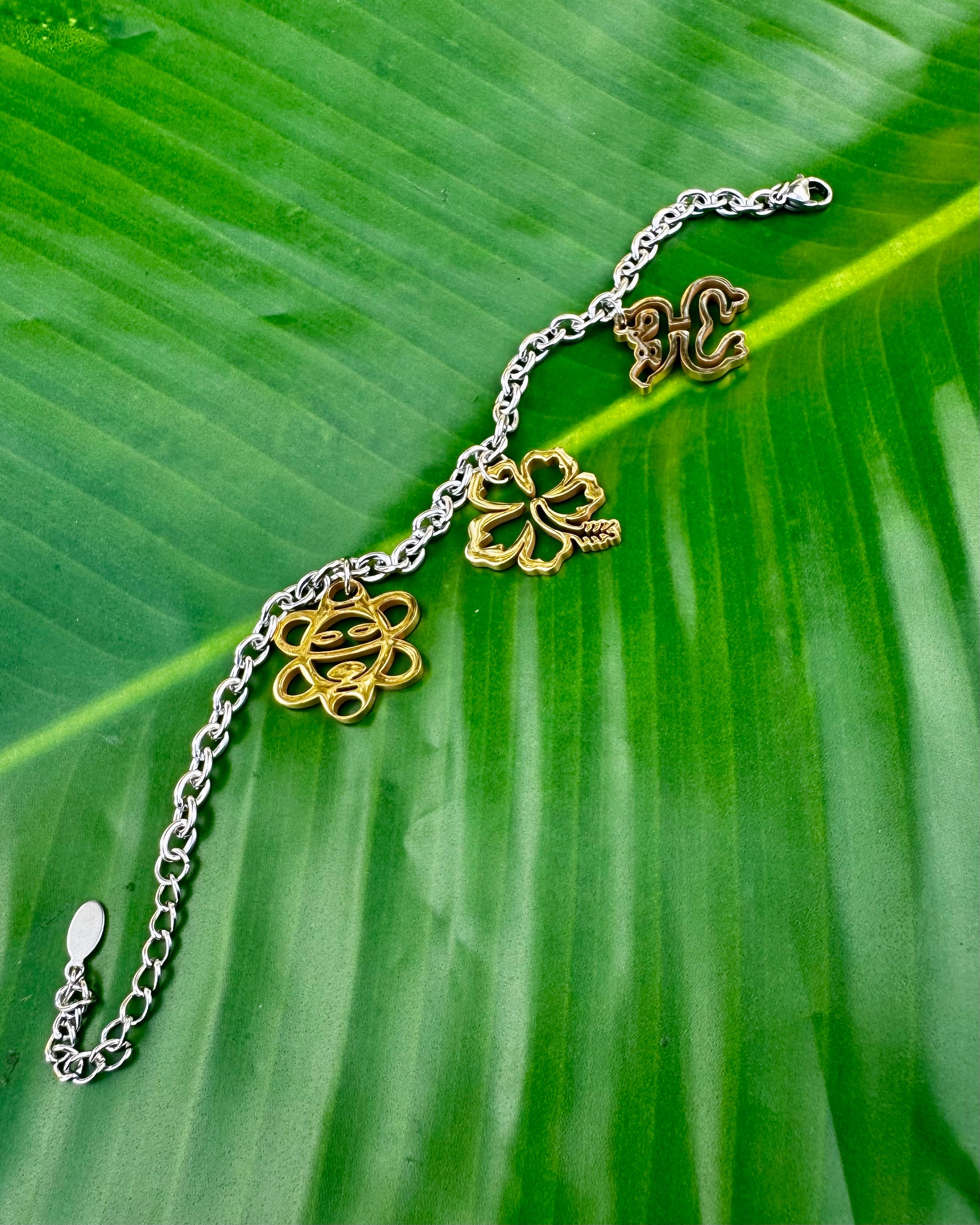 Puerto Rican jewelry bracelet featuring Maga flower, Coquí frog, and Sol Taíno charms in two-tone stainless steel.