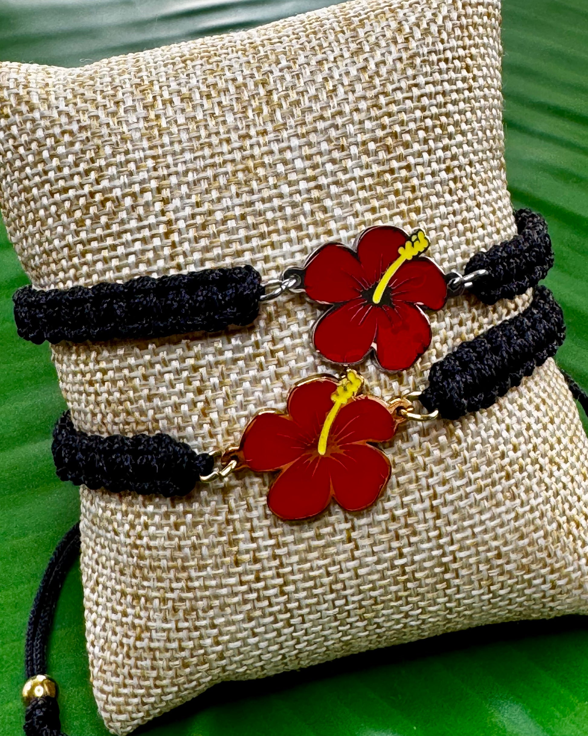 Black adjustable thread bracelet with a gold or silver Flor de Maga charm displayed on a neutral background.