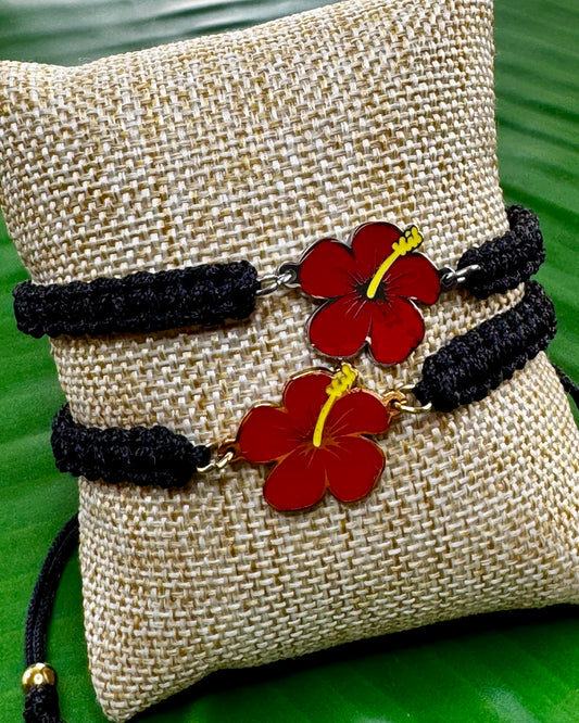 Black adjustable thread bracelet with a gold or silver Flor de Maga charm displayed on a neutral background.