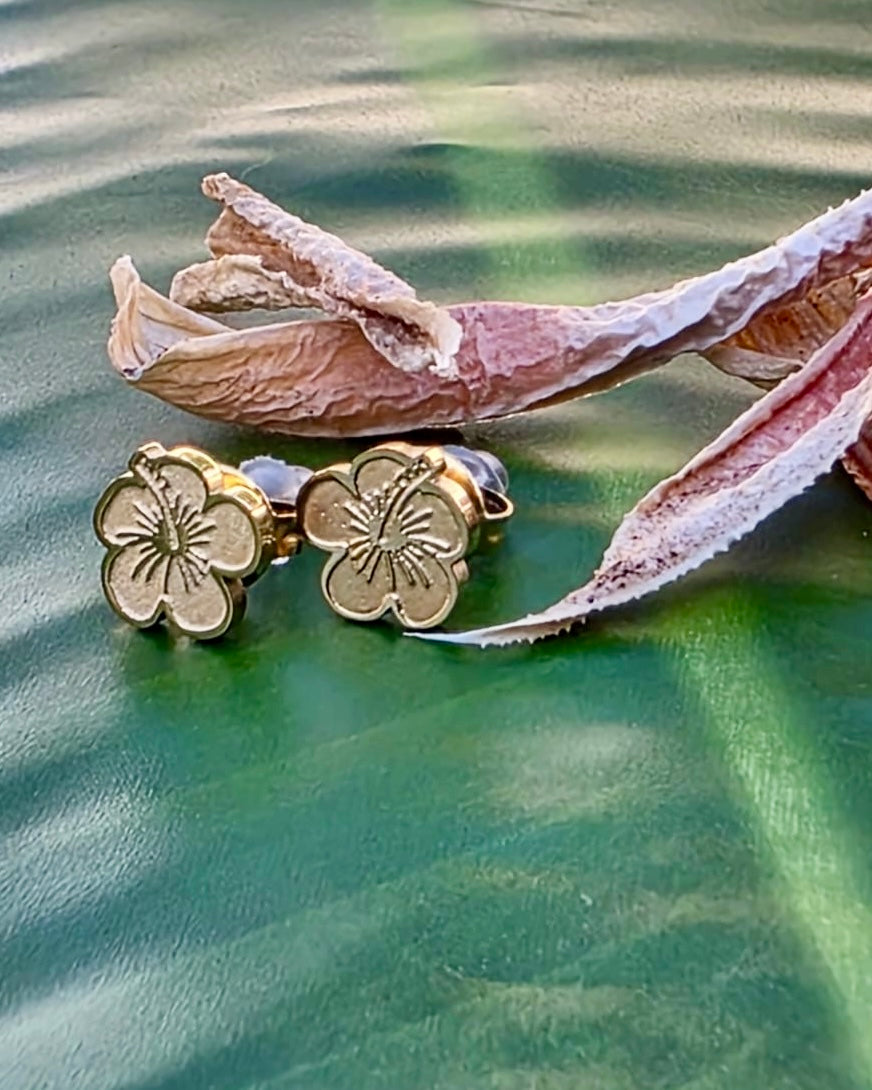 Small Flor de Maga stainless steel studs feature earrings in gold and silver tones made in Stainless Steel, inspired by Puerto Rico’s national flower.