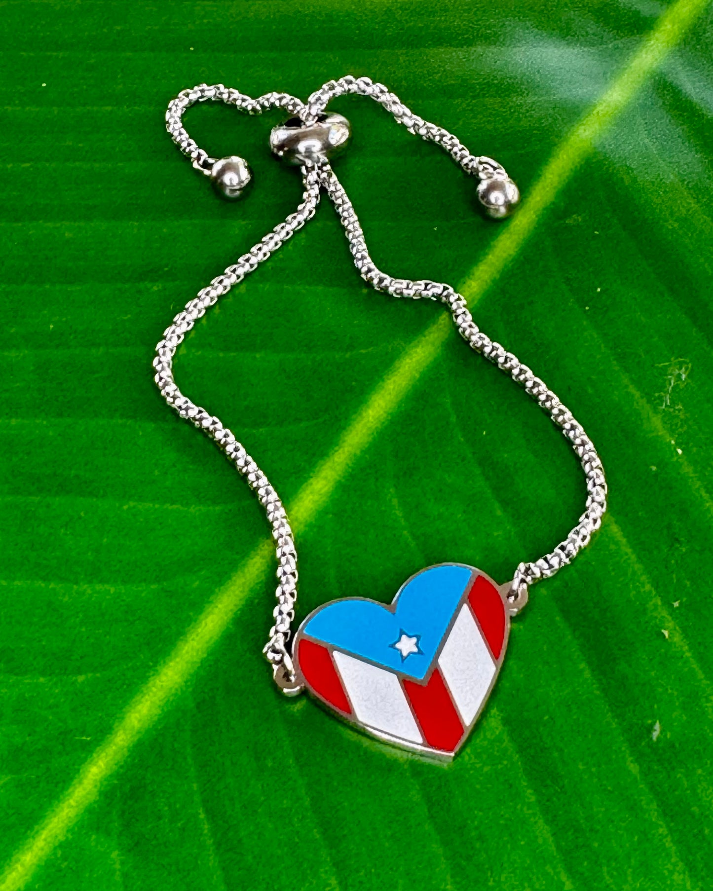 Adjustable stainless steel bracelet with a heart-shaped charm displaying the Puerto Rico flag, representing cultural pride, love, and connection to Puerto Rico.