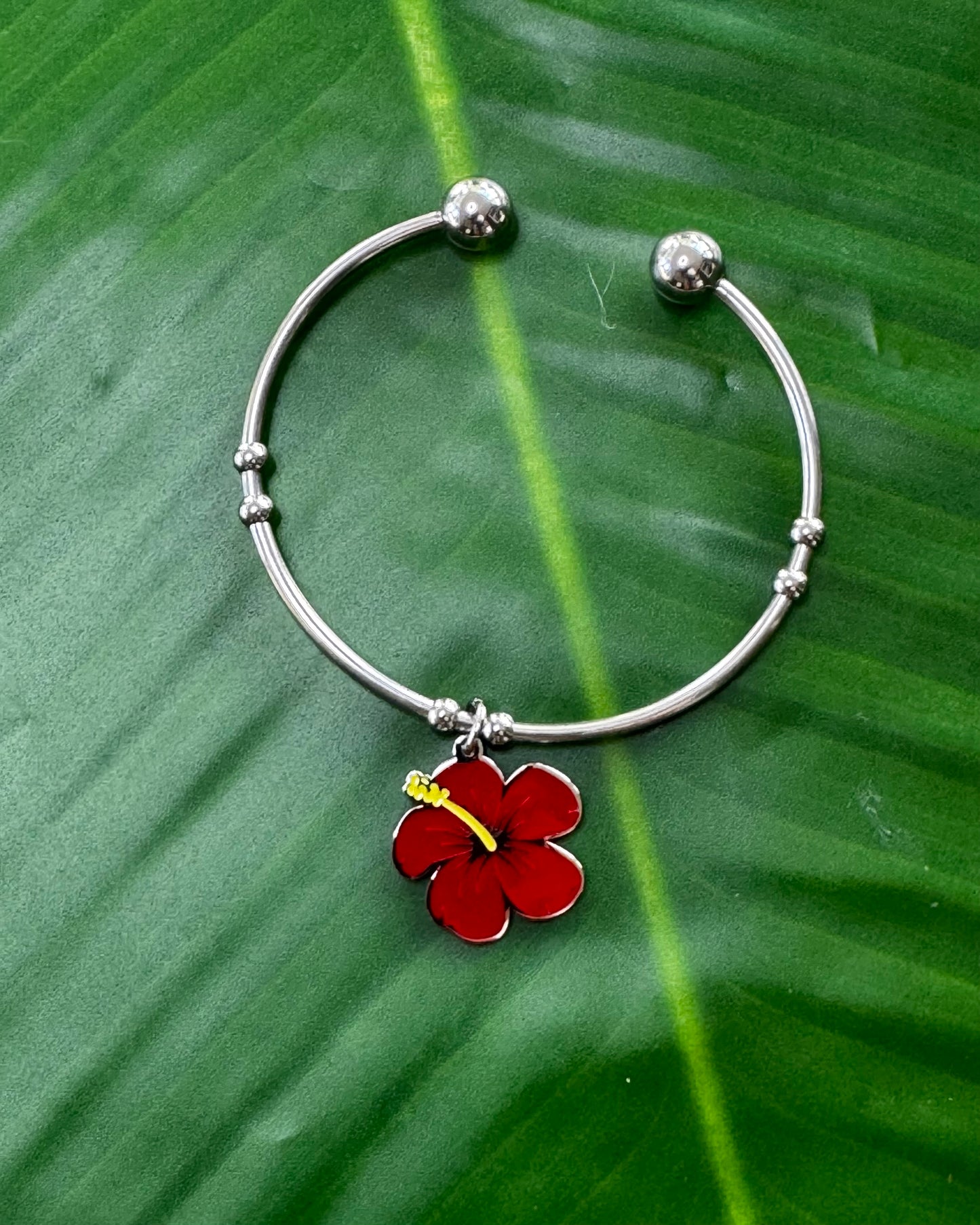 Stainless steel open bangle with a colored Flor de Maga charm.