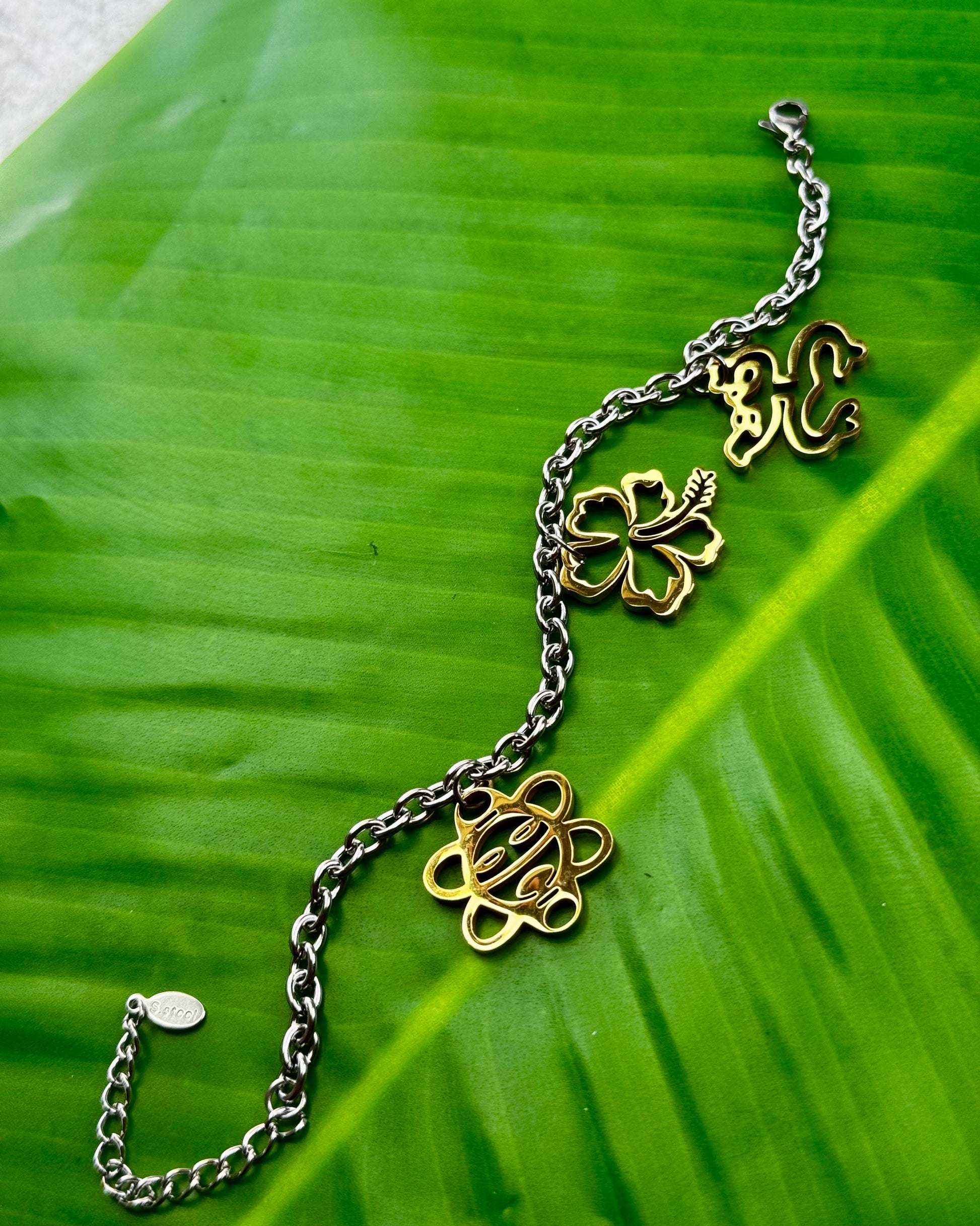 Puerto Rican jewelry bracelet featuring Maga flower, Coquí frog, and Sol Taíno charms in two-tone stainless steel.